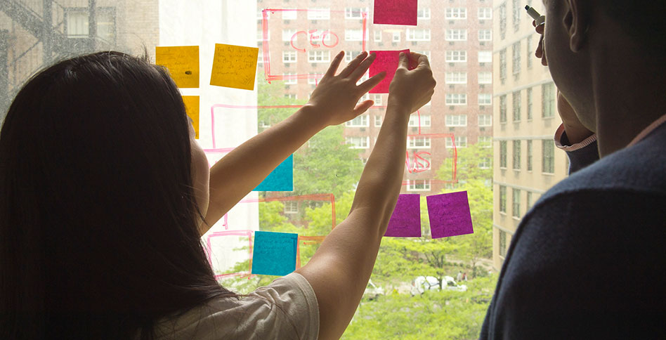 student posting sticky notes to organizational board student posting sticky notes to organizational board