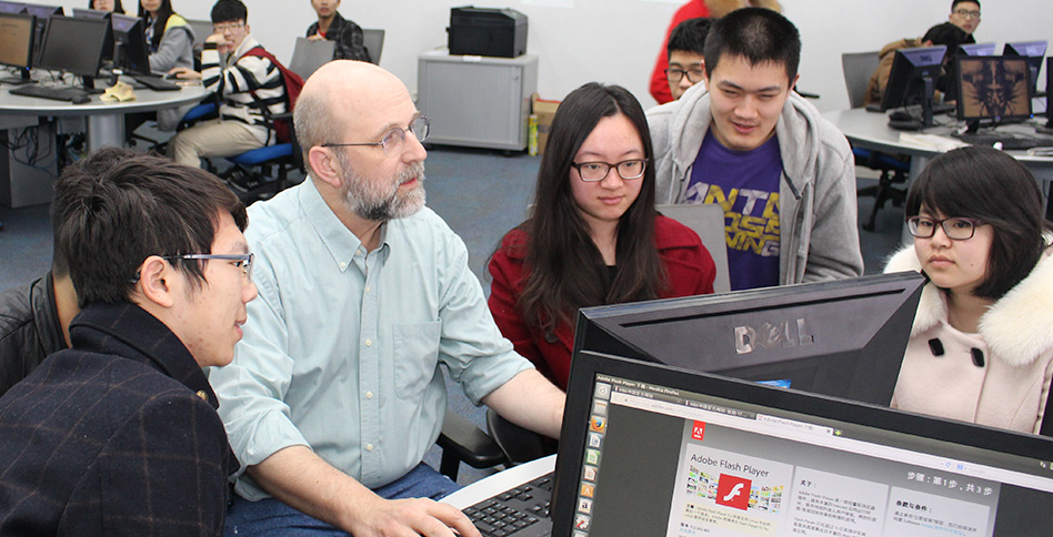 Students and professor working around computer Students and professor working around computer