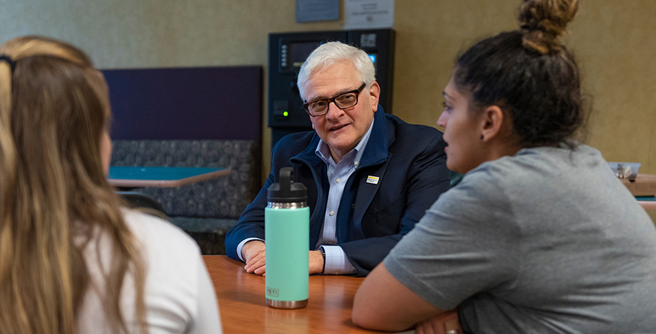 President Foley speaking with students around a table President Foley speaking with students around a table