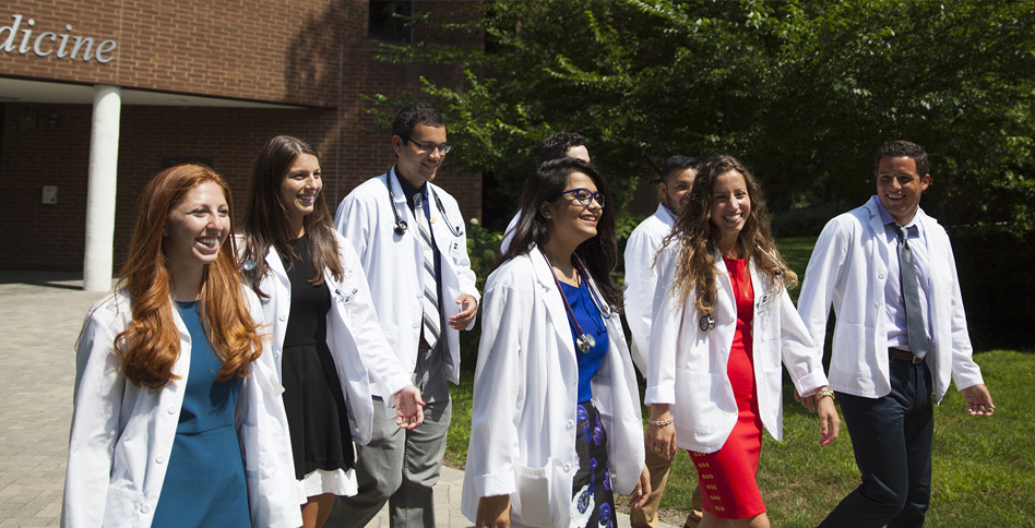Medical students in lab coats walking across campus