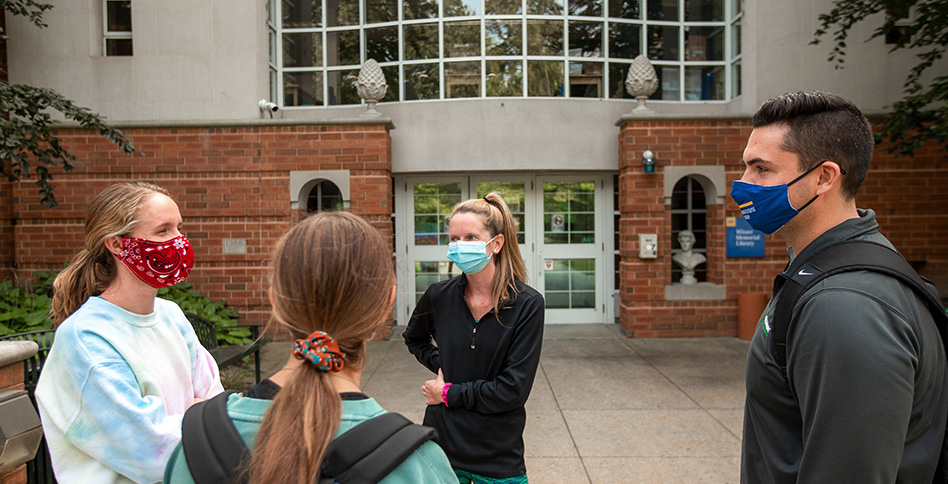 Masked students gathering outside of campus library