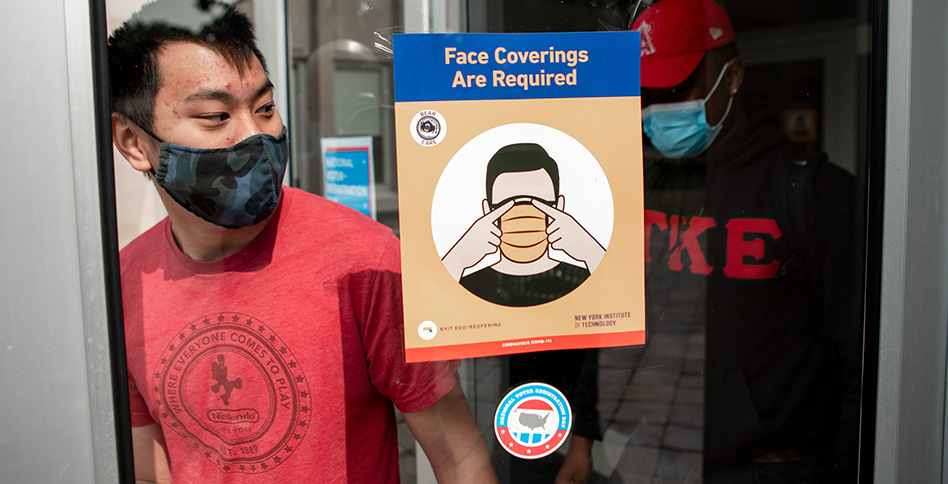 Student standing next to mask sign