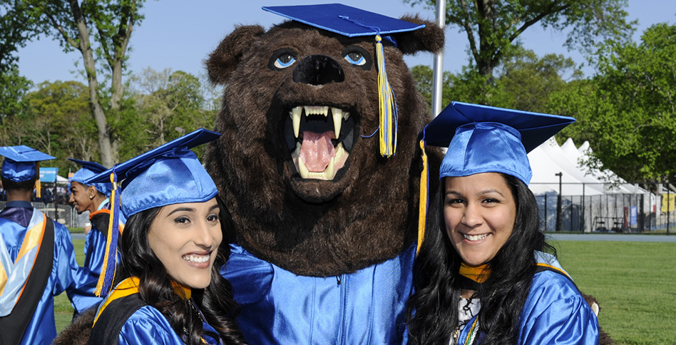 Graduates in cap and gown with Roary Bear mascot