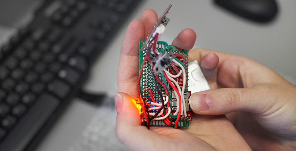 Hands holding circuit board with wires