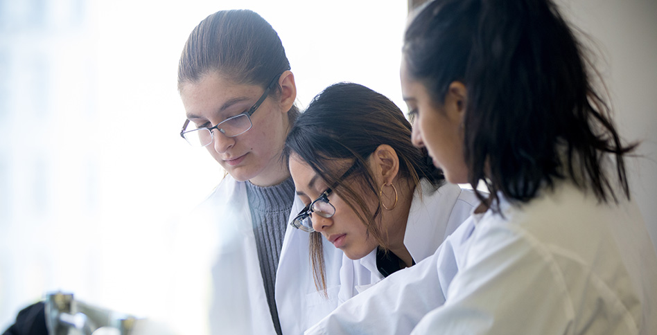 Three students in lab coats working
