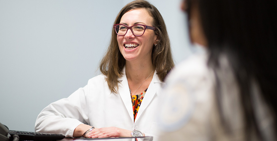 Female student in lab coat talking with others Female student in lab coat talking with others