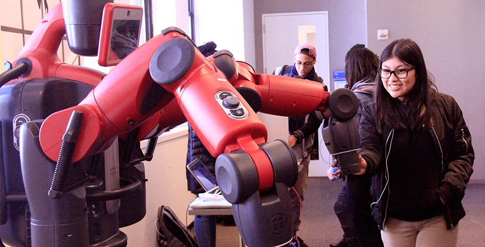 Students looks at robotic arm
