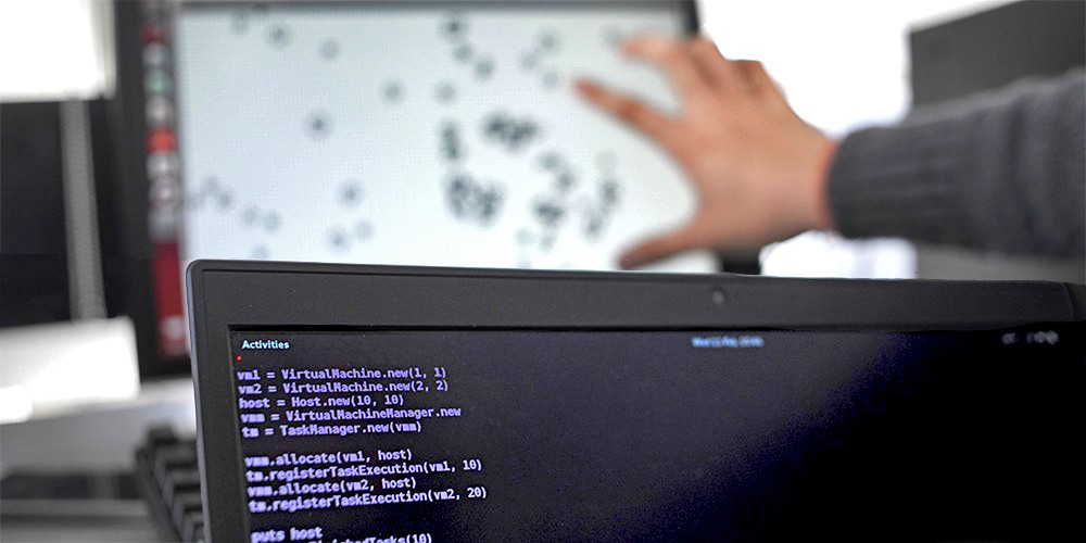 Hand pointing at computer screen with code.